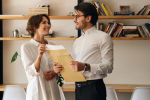 young attractive business colleagues standing with envelope letter while happily looking each other modern office_574295 5161